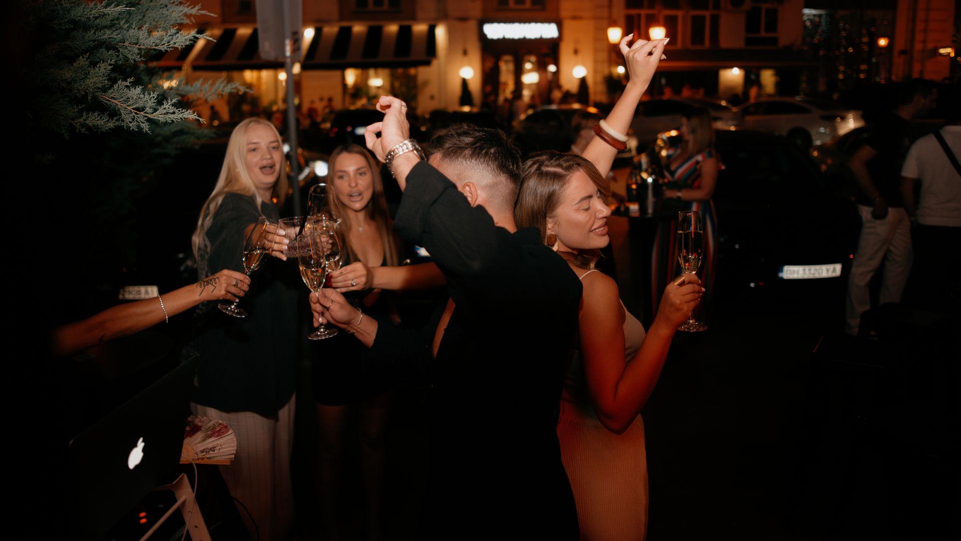 People dance and raise glasses during an outdoor gathering in Odesa, Ukraine, on Aug. 8, 2025.