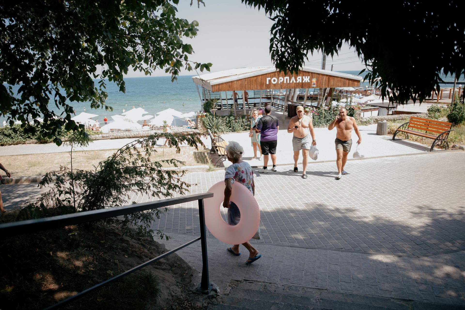 A woman carries a pink swim ring toward the beach in Odesa, Ukraine, on Aug. 9, 2025.