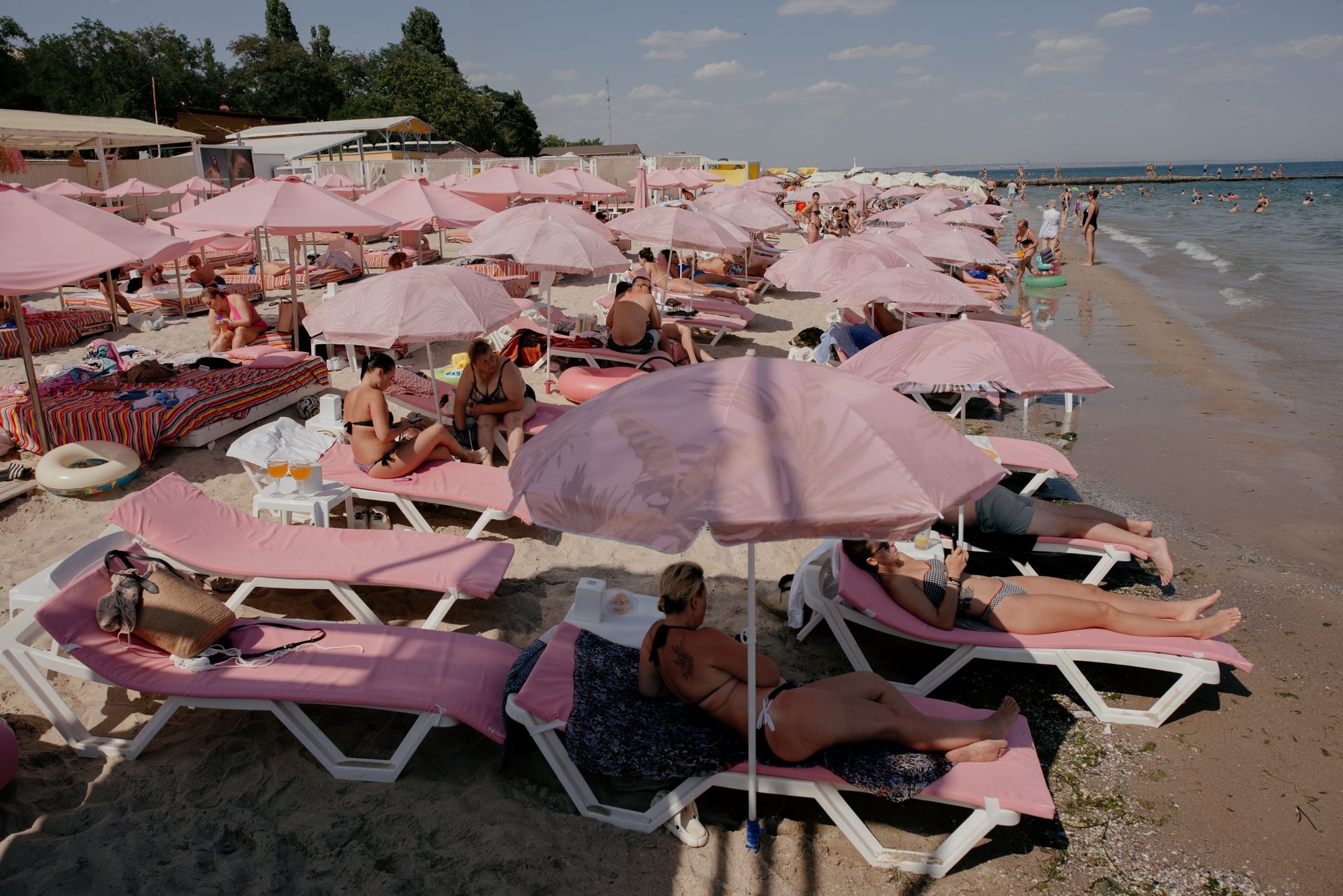 People lounge under rows of pink umbrellas at a beach in Odesa, Ukraine, on Aug. 9, 2025.
